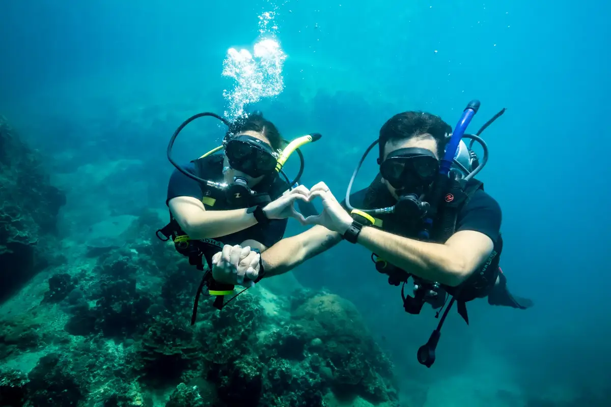 Two divers making a heart with their hands underwater